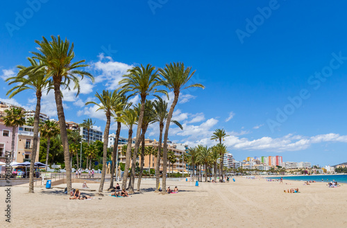 People relaxing under the palm trees on the beach in Villajoyosa, Spain