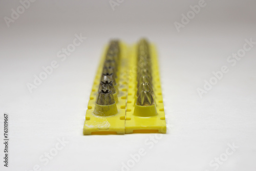 powder actuated tool loads. spent and new cartridges, inserted into pair of yellow strips, selective focus, close-up