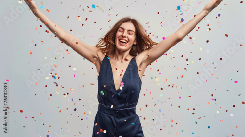 A jubilant woman raises her arms amidst a shower of confetti.