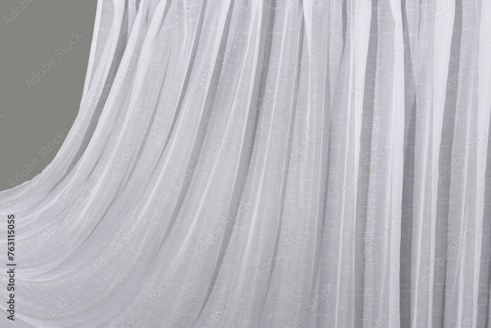 Obraz premium The white tulle curtain hangs in folds. The waves of the fabric are transparent and clean.