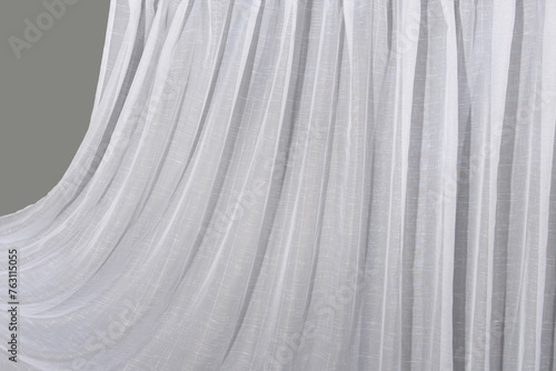 The white tulle curtain hangs in folds. The waves of the fabric are transparent and clean.