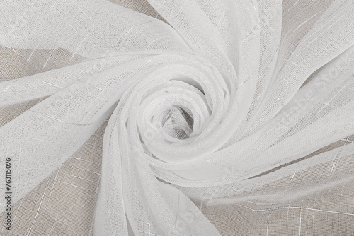 White tulle fabric rolled into a rose. The folds of the curtain are waves of a flower bud.