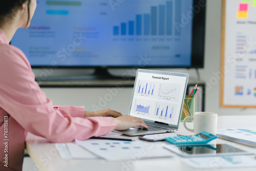 A businesswoman or accountant using laptop to analyze financial investments and business and marketing growth on a data graph. The concepts of accounting, economics, and commercial analysis.