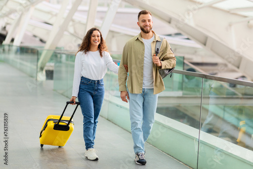 Relaxed young couple casually walking with luggage through the airport terminal