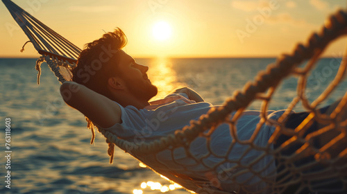 Young man lying in a hammock by the ocean and sunset view. A handsome guy is resting in a hammock against the backdrop of the mountains by the sea. photo