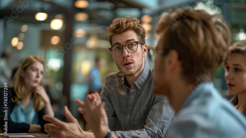 A young man in glasses actively engaging in a discussion at a business meeting.