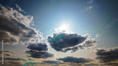 beautiful blue sky with dark dramatic cumulus clouds and sunlight for abstract background