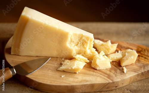 Grana Padano cheese on cutting board. Parmigiano Reggiano cheese on wooden board. Parmesan cheese on cutting board