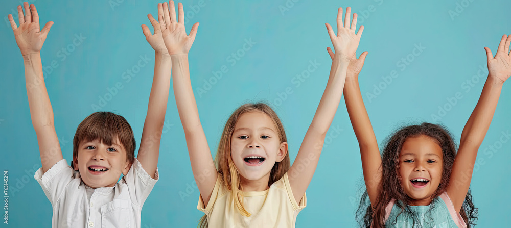 Happiness group children with their hands up on pastel blue background Happiness group children with their hands up on pastel blue background