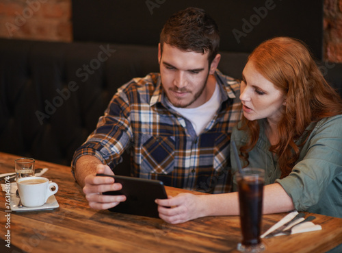 Couple  browsing and checking menu with tablet for dinner date  streaming or review at indoor restaurant. Young man and woman chilling or relax with technology for social media at cafe or coffee shop