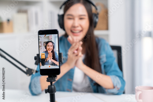 Selective focus phone in host channel of young beautiful Asian in creative broadcaster talking online explaining to promote marketing or consultant in daily life with listener at studio. Stratagem. © Summit Art Creations