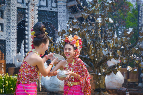 Songkran festival . Pretty Asian women playing with water-splashing Songkran. Beautiful Thai traditional dress costumes according to Thai culture to celebrate of the people Thailand New Year.