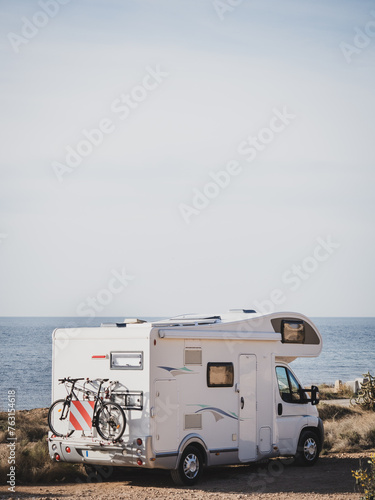 White over cab coachbuilt motor home parked by the sea