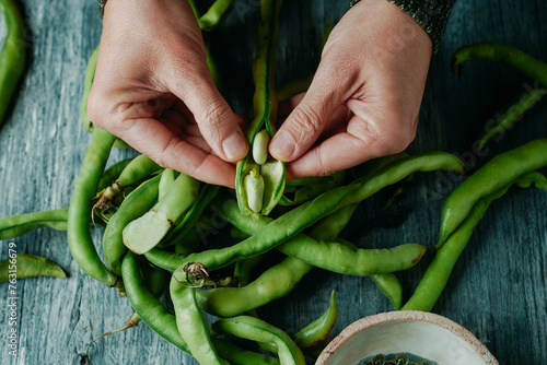 man takes some broad beans out of its pod