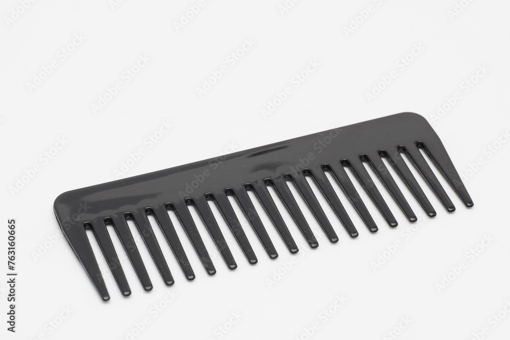 A large black plastic comb rotates on a white background. A large black plastic comb rotates on a white background.