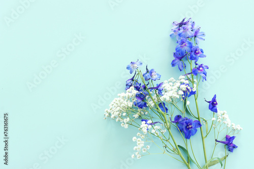 Top view image of violet delphinium flowers composition over mint background © tomertu