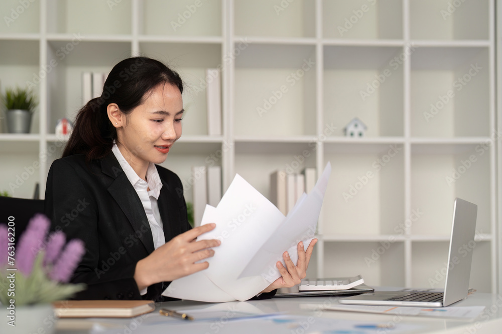 Young business woman asian or employee accounting bookkeeping documents checking financial data or marketing report working in office with laptop. Paperwork management Young business woman asian or employee accounting bookkeeping documents checking financial data or marketing report working in office with laptop. Paperwork management