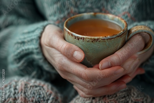 Close-up of a persons hands holding a cup of tea, showcasing comfort and warmth