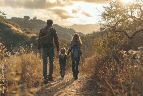 A man and two children walking together hand in hand along a dirt road in a scenic setting