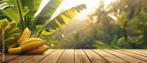 Ripe Bananas on Wooden Table in Tropical Setting, Ripe yellow bananas resting on a wooden table with a scenic backdrop of lush tropical greenery and banana trees. photo