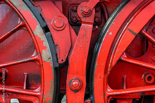 Two red wheels of an old steam locomotive with brake