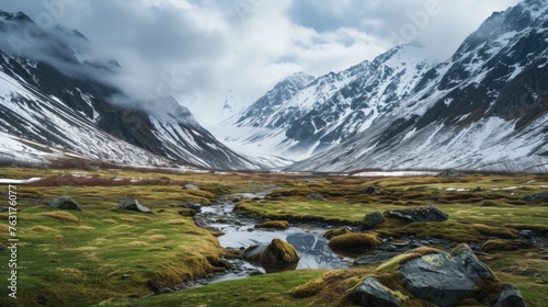 A tranquil stream meanders through a moss-covered valley, with mist-shrouded mountain peaks in the background