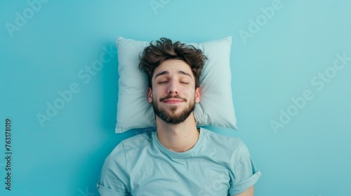 a young man sleeping on pillow isolated on pastel blue colored background Sleep deeply peacefully rest. Top above high angle view photo portrait of satisfied .senior wear blue shirt