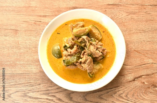 spicy boiled slice pork meat with eggplant in coconut milk green curry soup on plate