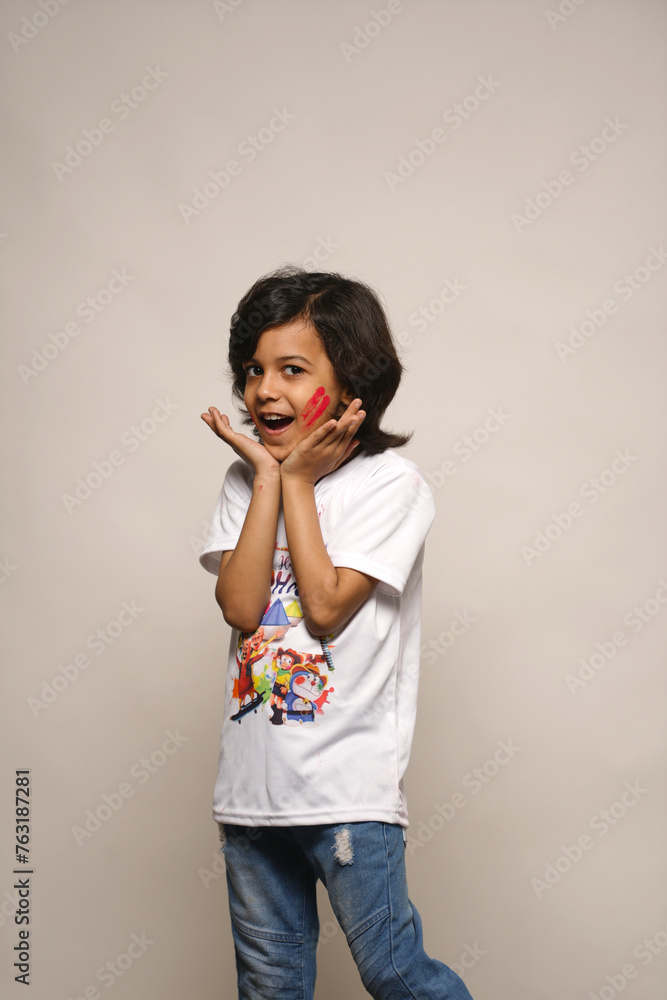 Young kid boy celebrating holi standing isolated on plain background Young kid boy celebrating holi standing isolated on plain background