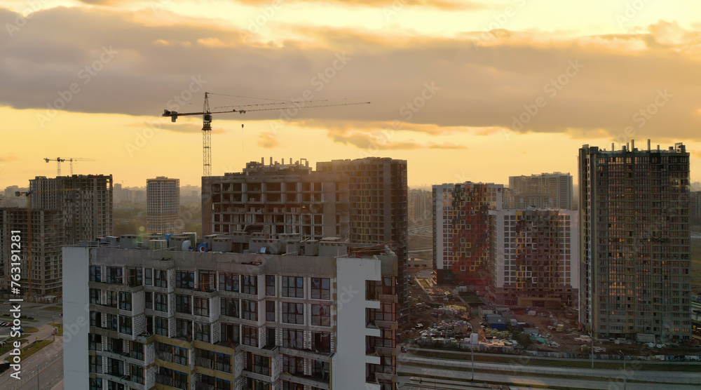 Tower crane in action on sunset. Construction site with building construction. Housing renovation and real estate. Crane during formworks. New Housing and residential buildings construction. Tower crane in action on sunset. Construction site with building construction. Housing renovation and real estate. Crane during formworks. New Housing and residential buildings construction.