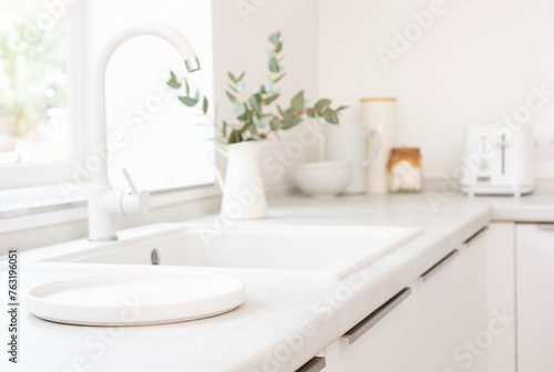 Empty round tray for product display on blurred kitchen sink counter and window sill background