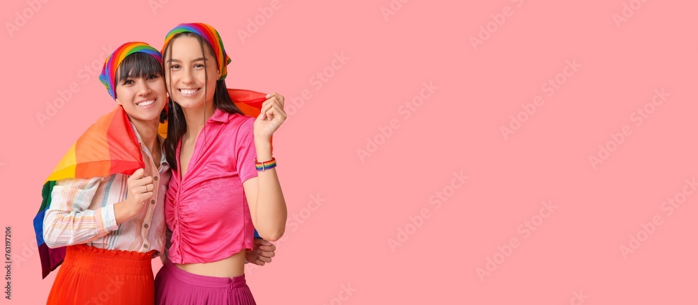 Young lesbian couple with LGBT flag on pink background with space for text Young lesbian couple with LGBT flag on pink background with space for text