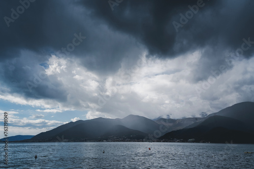 Thunderclouds over a frosty bay with mountains, dramatic sky with cumulus clouds, nature and meteorology abstract background