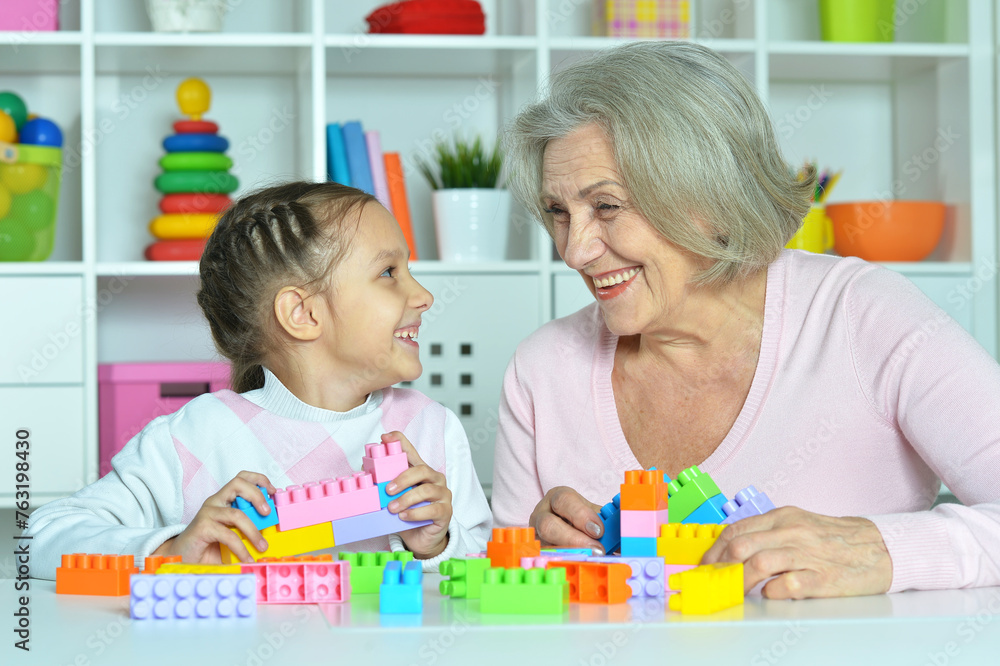 Cute girl and grandmother playing with colorful plastic blocks Cute girl and grandmother playing with colorful plastic blocks
