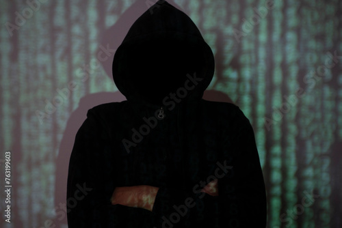 The hacker stood in the shadows with his arms crossed. photo