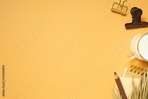 Obraz na płótnie Workspace concept. Note, memo pad, clip, colored pencil, cup of milk, plant on orange desk background. flat lay, top view, copy space w salonie