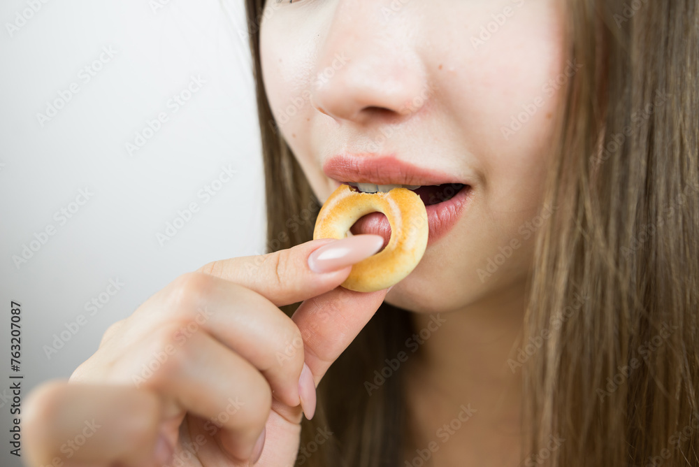 young beautiful girl eating bagels, close-up, crop photo.Attractive brunette sexy woman eating a delicious donut. young beautiful girl eating bagels, close-up, crop photo.Attractive brunette sexy woman eating a delicious donut.