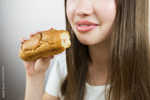 young beautiful girl eating a croissant, close-up, crop photo. female mouth eating croissant