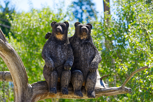 Two wooden bears sitting on branch at Predjama castle on a sunny summer day. Photo taken August 11th, 2023, Predjama, Slovenia. photo