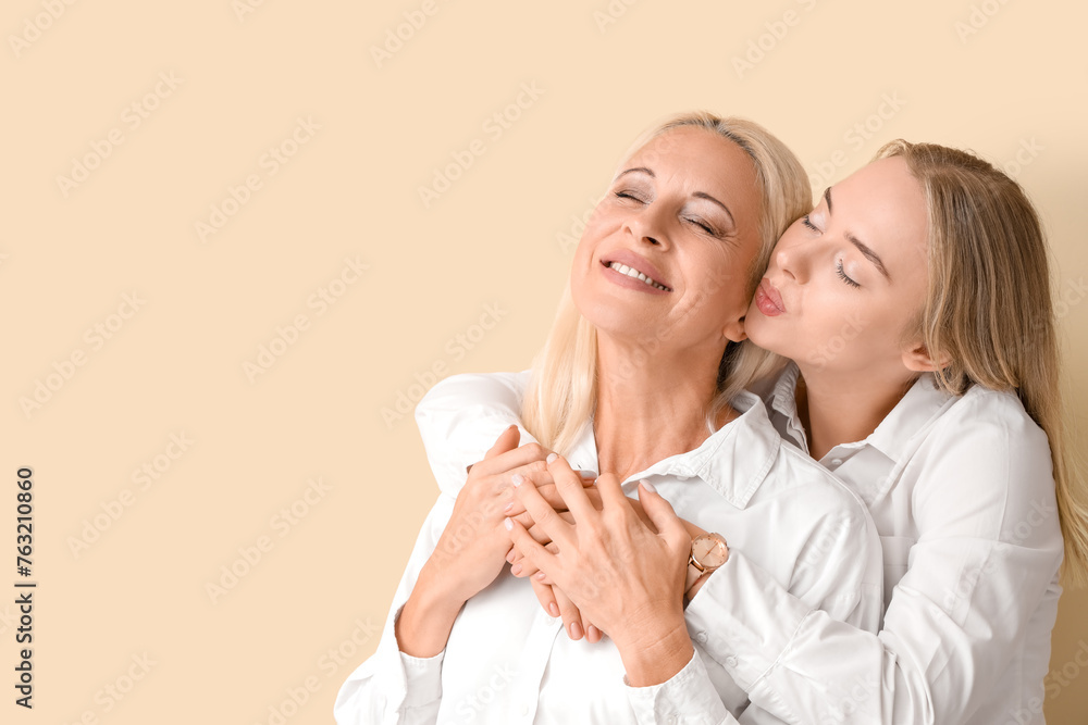 Happy young beautiful woman and her mother hugging on orange background Happy young beautiful woman and her mother hugging on orange background