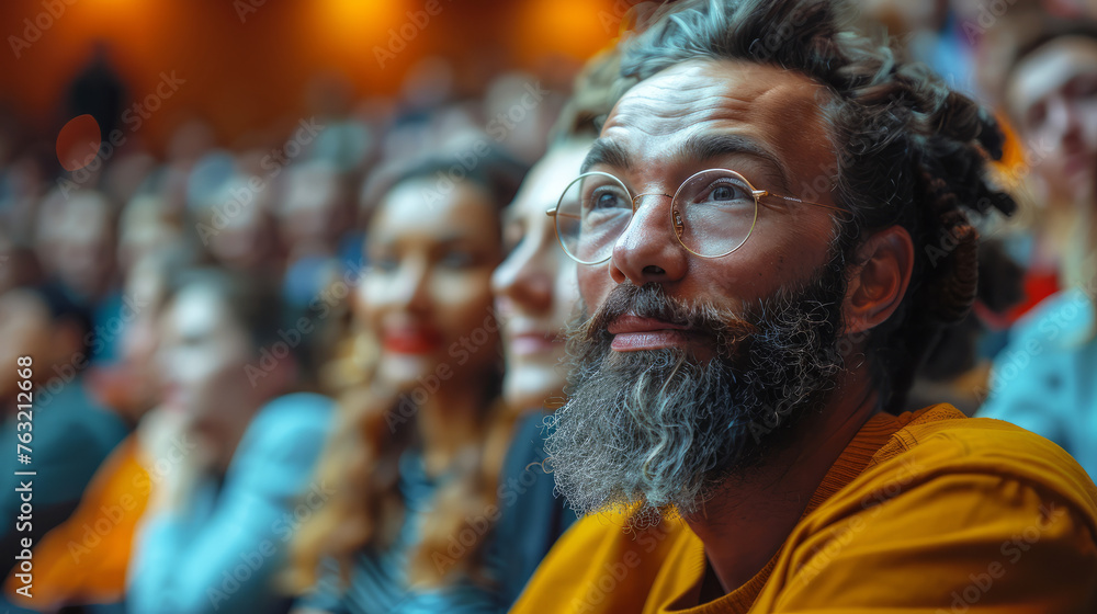 A man with a beard and glasses is sitting in a crowd of people. diverse group of students and educators from different cultures in a lecture hall, Modern university lecture delivering an AI-focused