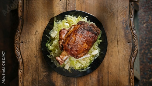 beautiful meat showcase, shop counter, Golden-brown pork knuckle on cabbage in a black skillet on a wooden table