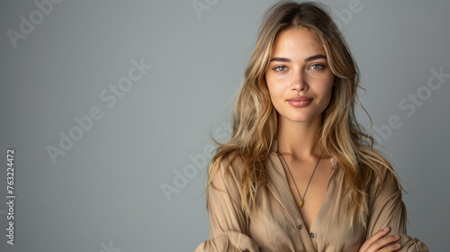 Pretty smiling joyfully female with fair hair, dressed casually, looking with satisfaction at camera, being happy. Studio shot of good-looking beautiful woman isolated against blank studio wall. © standret