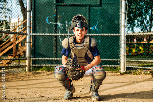 Young teen boy play baseball on a playground wearing catcher clothes