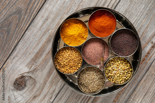 Quadro su tela Indian spices box or Indian masala dabba with seven containers on rustic wooden table