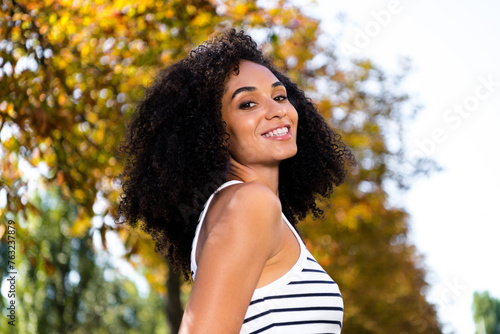 Photo of positive optimistic shiny woman spending free time waking alone in park on sunny warm day