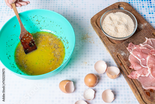 Stirring the egg with garlic and parsley for pork breading. photo