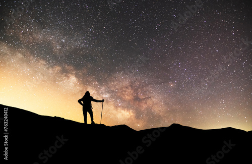 Silhouette of a hiker standing on the hill, on the milky way galaxy background. © Inga Av