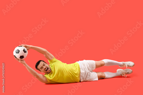 Portrait of male football player catching ball on red background