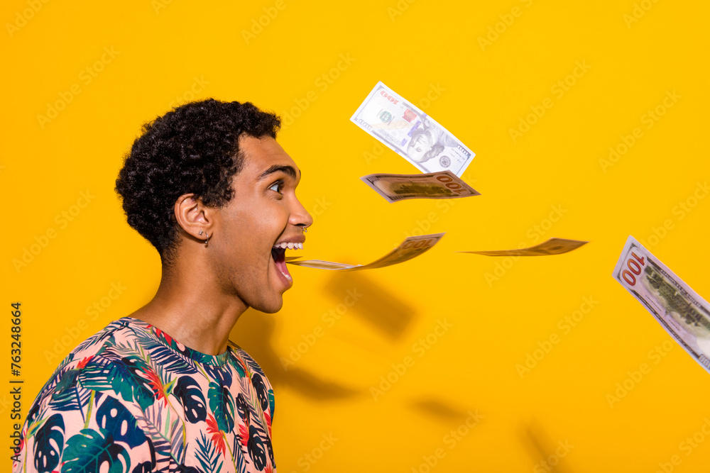 Side profile photo of funny crazy student man open mouth screaming spitting banknotes spend money isolated on yellow color background - obrazy, fototapety, plakaty 